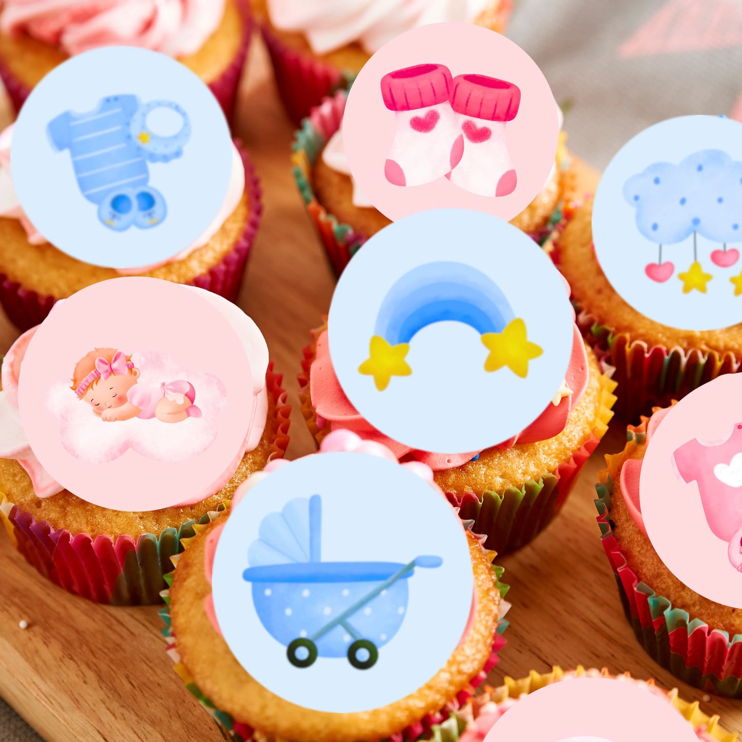 a mix of pink and blue cute illustrated cake toppers on frosted cupcakes in colourful cases