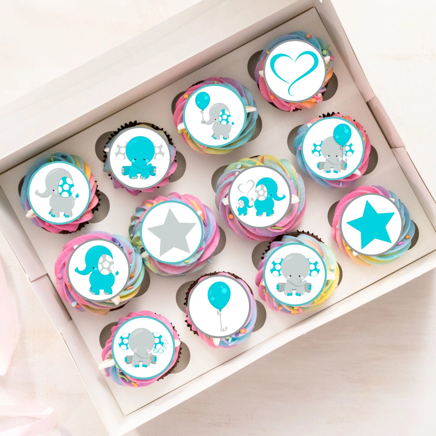 top view of a tray of rainbow cupcakes with edible cupcake toppers with cute blue elephant design