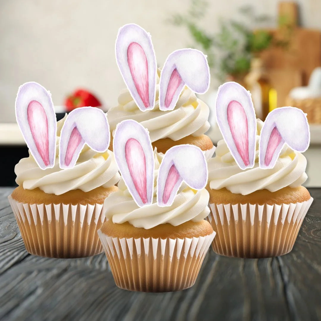 Edible wafer Easter bunny ears on white frosted cupcakes on a kitchen counter
