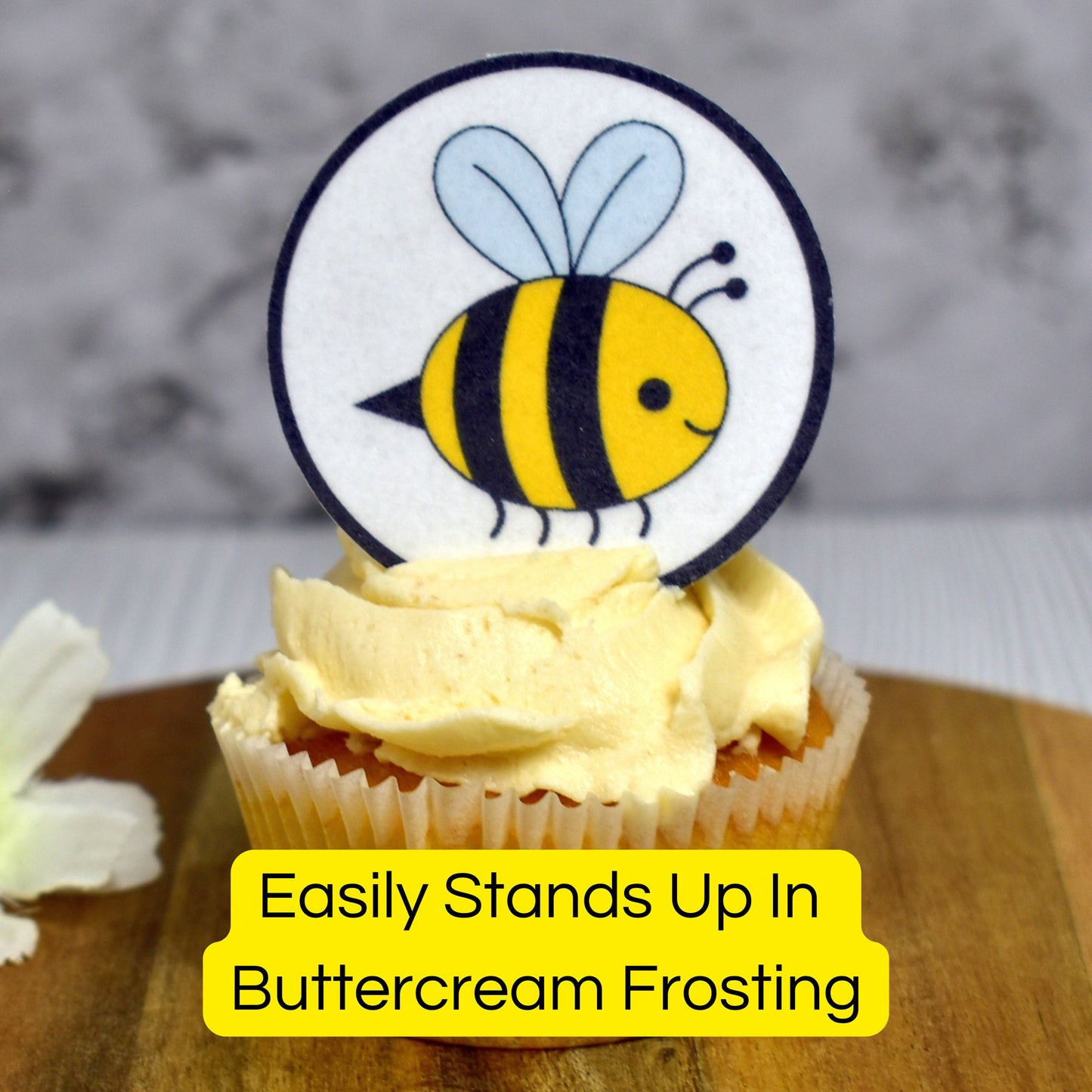 Cupcake with a bee-themed cupcake topper on a wooden board.