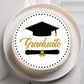 Graduation-themed cake with a black and gold design on a white plate.