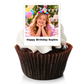 A chocolate cupcake in a brown paper liner with white frosting, topped with a printed custom photo insert that reads 'Happy Birthday Sophie' on a white background.
