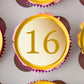 gold coloured cupcake topper with the number 16, placed on pink frosted cupcakes