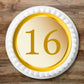 gold coloured cake topper with the number 16, placed on white frosted cake