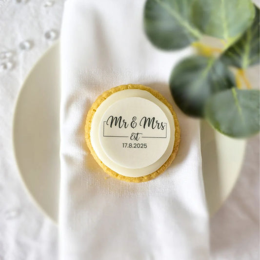 black and white classic mr and mrs personalised edible toppers placed on a biscuit on a wedding table