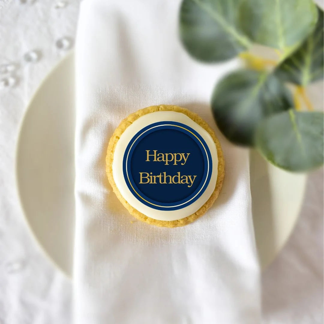 navy happy birthday cookie decoration with gold font, placed on a biscuit