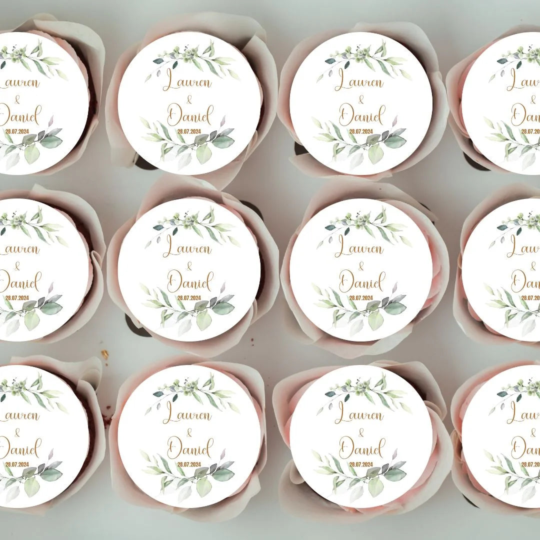 green foliage designed edible wafer disc with personalised name and date in gold lettering shown on cupcakes in a box