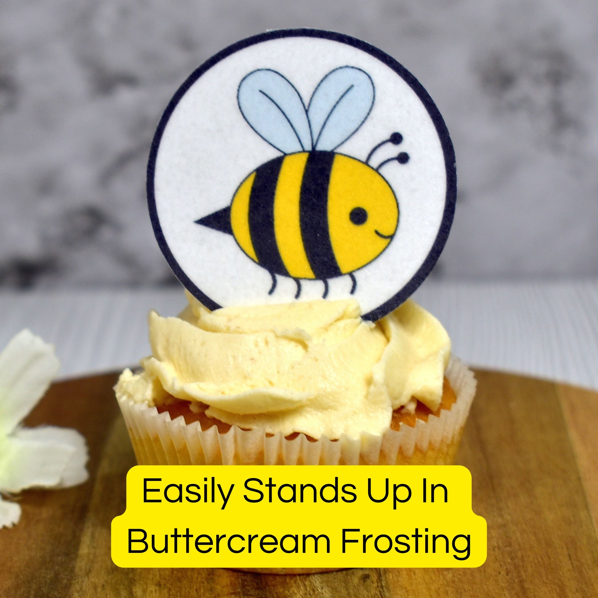 Cupcake with a bee-themed cupcake topper on a wooden board.