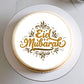 Round cake with 'Eid Mubarak' text on a white plate