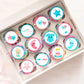 tray of rainbow frosted cupcakes topped with Gender Reveal Edible Cupcake Toppers with pink and blue illustrations