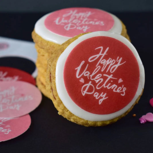 red and pink edible cookie decorations on white iced biscuits