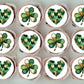 Cupcakes with green and white designs resembling shamrocks and hearts on a light gray background.