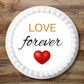 red heart "love forever" edible cake topper placed flat on a white cake