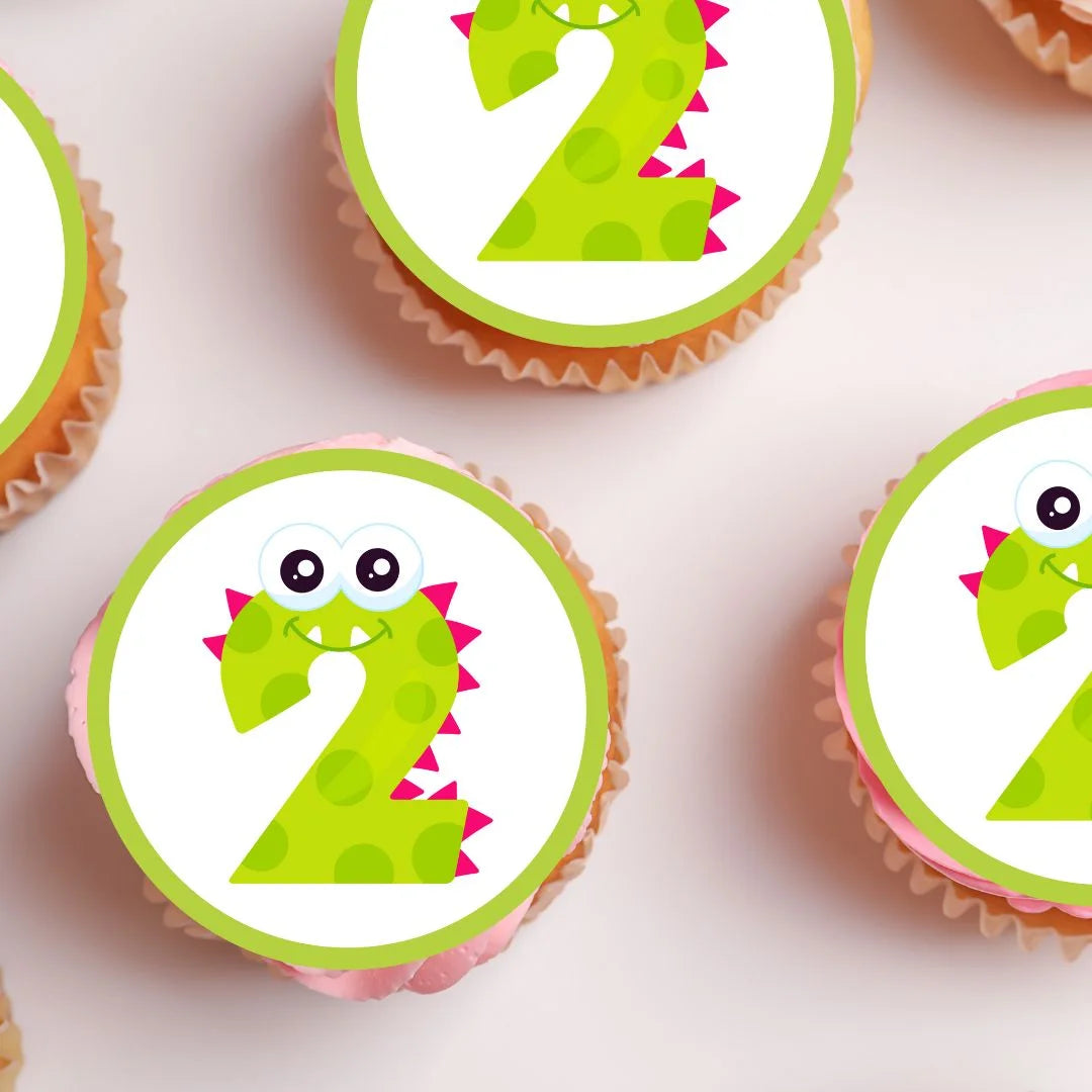 edible cupcake toppers with a green monster themed number 2 on white frosted cupcakes