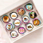 top view of a tray of cupcakes with colourful frosting and finished with round cupcake toppers featuring photos of cute puppies