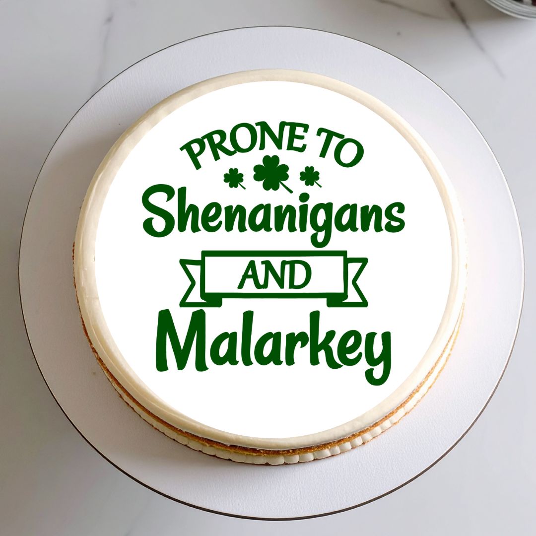 Round cake with green text 'Prone to Shenanigans and Malarkey' on a white plate.