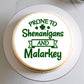 Round cake with green text 'Prone to Shenanigans and Malarkey' on a white plate.
